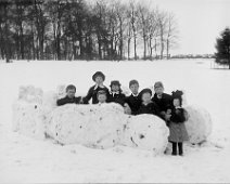 8 children in snow fort on hill Original caption: 8 children in snow fort on hill