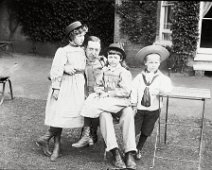 Mr. D. with 3 children in front of drawing room window Sedgeford Hall Original caption: Mr. D. with 3 children in front of drawing room window