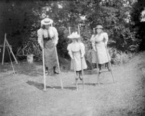 3 girls on stilts Original caption: 3 girls on stilts