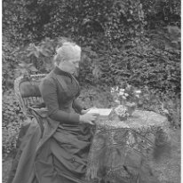 Mother reading at table in garden Original caption: Mother reading at table in garden