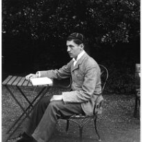 Purdy sitting at garden table with book Original caption: Purdy sitting at garden table with book