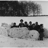 8 children in snow fort on hill Original caption: 8 children in snow fort on hill