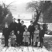 Miss. B. with 9 children in snow Sedgeford Hall Original caption: Miss. B. with 10 children in snow