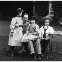 Mr. D. with 3 children in front of drawing room window Sedgeford Hall Original caption: Mr. D. with 3 children in front of drawing room window