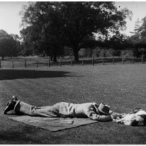 Man and dog lying on grass Original caption: Man and dog lying on grass