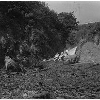 Beach party in the rocks Maybe taken from Mill Bay. Is that Wood Grange on the skyline? Original caption: Beach party in the rocks