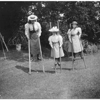 3 girls on stilts Original caption: 3 girls on stilts