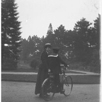 Girl with boy in sailor suit on bicycle Original caption: Girl with boy in sailor suit on bicycle