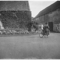 Woman with bicycle going through farm gate Sedgeford Hall Original caption: Woman with bicycle going through farm gate